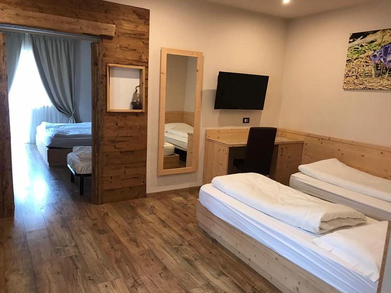 Helles Schlafzimmer mit Holzboden, zwei Einzelbetten, großem Spiegel und Flachbildfernseher.