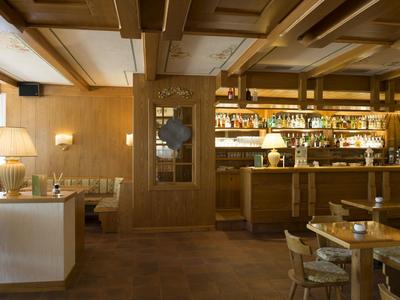 Gemütliche Hotelbar mit Holzverkleidung, sitzenden Gästen und einer gut bestückten Theke.