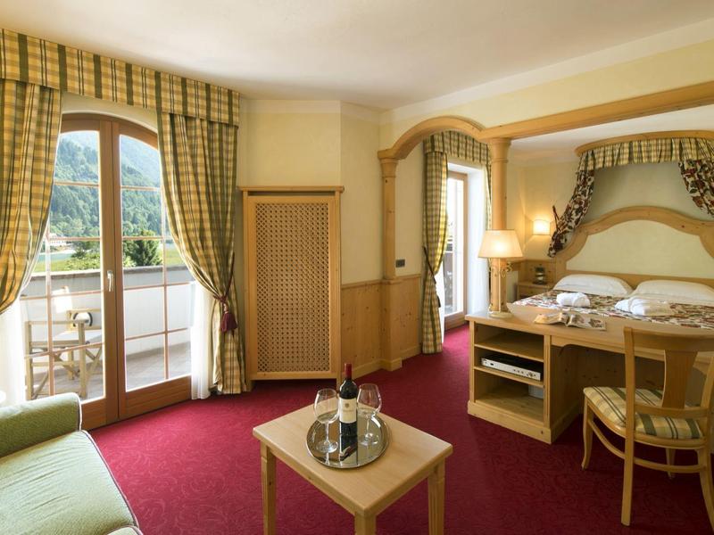 Helles Hotelzimmer mit Doppelbett, Balkon und Blick auf grüne Berge