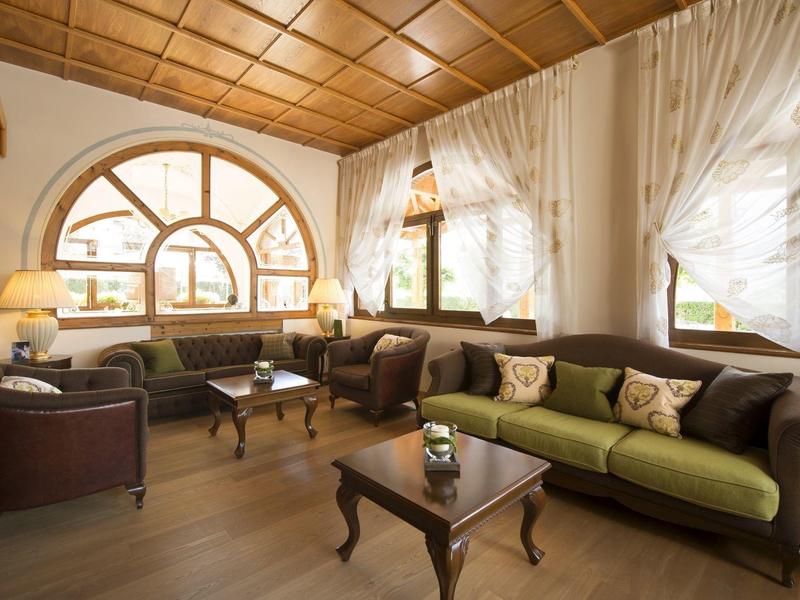 Heller Hotel-Warteraum mit grünen und braunen Sofas, Holztisch und großem Fenster