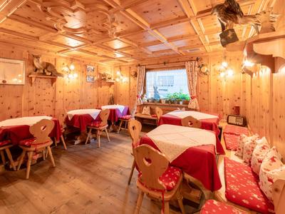 Cozy wood-paneled dining area with red tablecloths and cushions in a hotel.