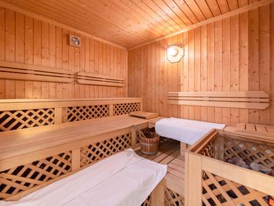 Wooden sauna with benches, wooden walls, and towels on loungers for relaxation.