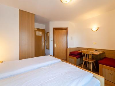 Cozy hotel room with two beds, wooden furniture, and a seating area with table and chairs.