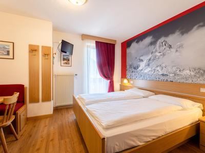 Bright hotel room with double bed, wall art, and wooden flooring.