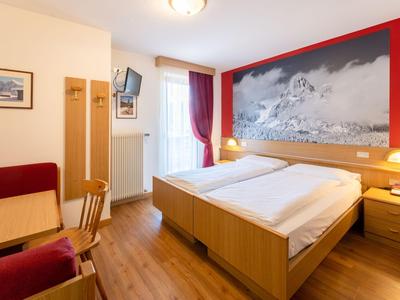 Brightly furnished hotel room with double bed, wooden floor, and large photo on the wall.