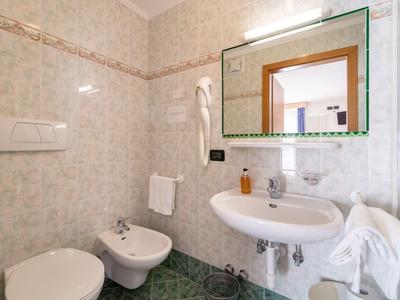 Compact bathroom with toilet, bidet, sink, and mirror in neutral tones.