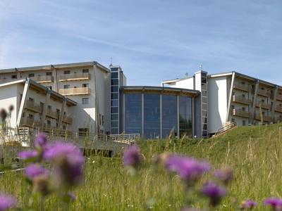 Modernes Hotel mit großen Fensterfronten und grasbewachsenem Hügel im Vordergrund