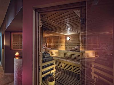 Gemütliche Sauna mit Holzbänken und gedämpftem Licht in einem Wellnessbereich.