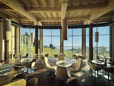 Modernes Hotelrestaurant mit großen Fenstern und Blick auf die Landschaft.
