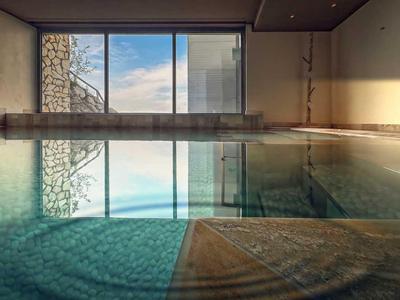 Innenpool mit großen Fenstern und Blick auf den Himmel, helles und ruhiges Ambiente.