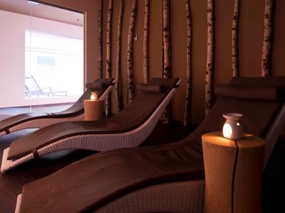 Dunkler Entspannungsraum mit Liegestühlen und warmem Licht für Wellnessurlaub.