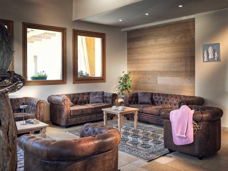 Gemütliche Hotellounge mit braunen Ledersofas, Teppich und Holzwänden.