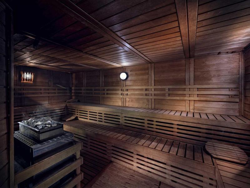 Ein dunkler, holzverkleideter Sauna-Raum mit Sitzbänken und einem Saunaofen.