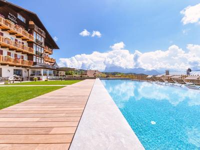 Hotel con piscina a sfioro, terrazza soleggiata e vista sulle montagne sotto un cielo limpido
