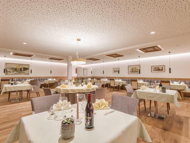 Heller, gemütlicher Speisesaal mit mehreren gedeckten Tischen, Holzfußboden und Kunst an den Wänden.