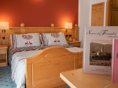 Gemütliches Schlafzimmer mit Holzbetten, Nachttischen, roten Wänden und blauem Teppich.