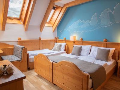 Gemütliches, holzgetäfeltes Schlafzimmer mit zwei Betten, blauer Wand und Dachfenstern.