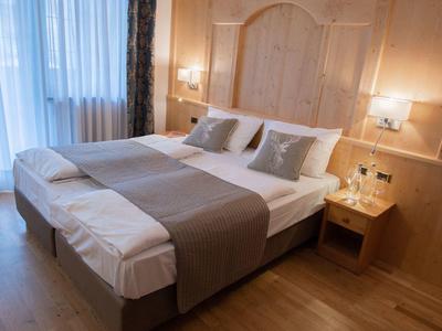 Hell eingerichtetes Schlafzimmer mit großem Bett, Holzwänden, Nachttisch und sanfter Beleuchtung.