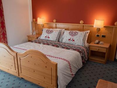 Gemütliches Schlafzimmer mit Holzbett, roter Wand, Teppichboden und Nachttischen mit Lampen.