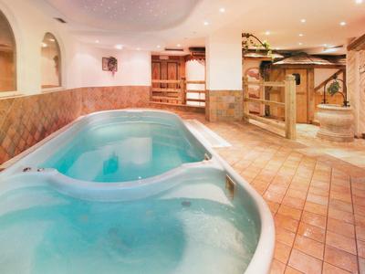 Innenbereich mit ovalem Schwimmbecken und Holz- sowie Fliesenböden in warmen Farbtönen.