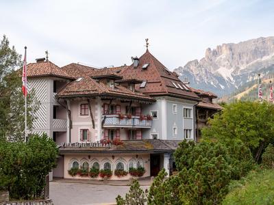 Hotel with traditional architecture against mountain backdrop under cloudy sky