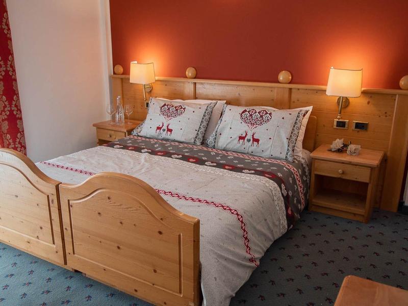 Gemütliches Schlafzimmer mit Holzbett, roter Wand, Teppichboden und Nachttischen mit Lampen.