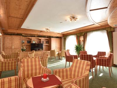 Cozy hotel lounge area with striped armchairs and large windows with curtains.