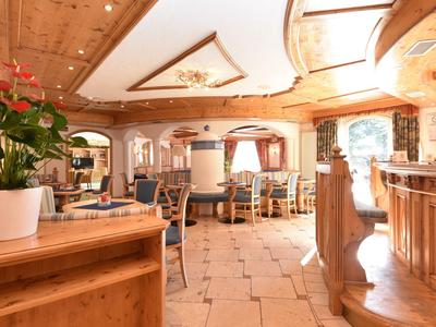 Helles Restaurant mit Holzdecke, cremefarbenem Boden und gemütlichen Sitzbereichen mit Stühlen.