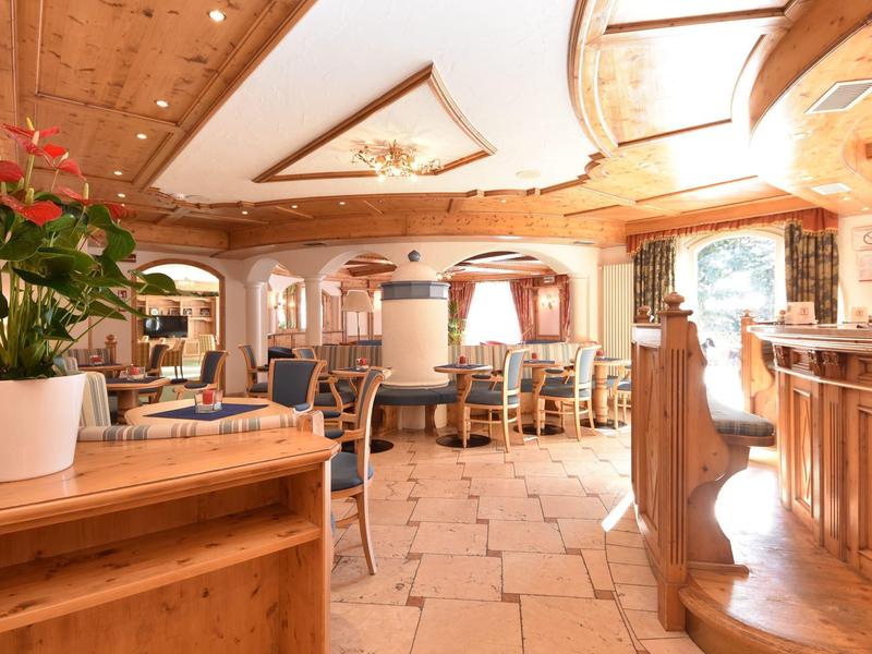 Helles Restaurant mit Holzdecke, cremefarbenem Boden und gemütlichen Sitzbereichen mit Stühlen.