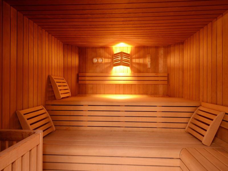 Innensauna mit Holzverkleidung, Sitzbänken und warmem, indirektem Licht.