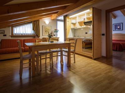 Gemütlicher Wohnbereich mit Holzboden, Esstisch, Küche und angrenzendem Schlafzimmer.