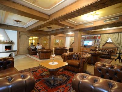 Gemütliches Wohnzimmer mit dunklen Ledersesseln, Teppich, Holzdecken und Kamin im Hintergrund.