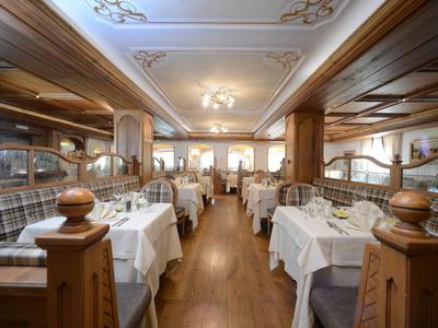 Elegantes Restaurant mit weißen Tischdecken, Holzmöbeln und warmem Licht.