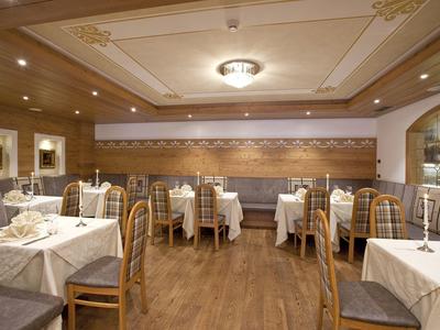 Stilvolles Restaurant mit Holzwänden, gedeckten Tischen und bequemen Stühlen in warmem Licht.