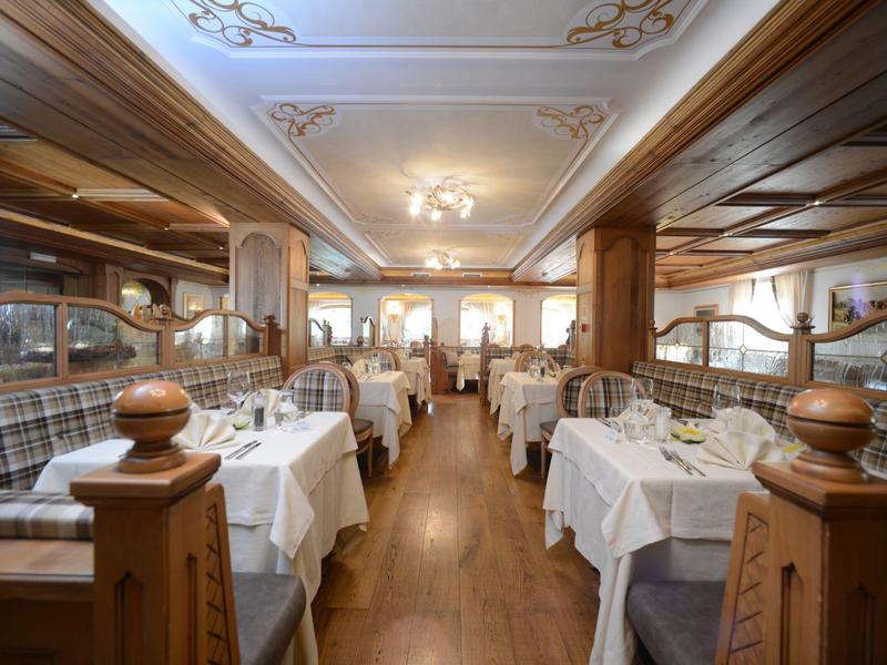 Elegantes Restaurant mit Holzmöbeln, weißen Tischdecken und gemütlichen Sitzbereichen mit Polstern.