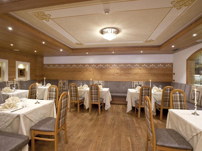 Stilvolles Restaurant mit Holzwänden, gedeckten Tischen und bequemen Stühlen in warmem Licht.