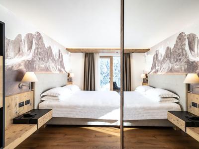 Habitación de hotel moderna con cama doble, suelo de madera, papel pintado de montaña, acogedora y luminosa.