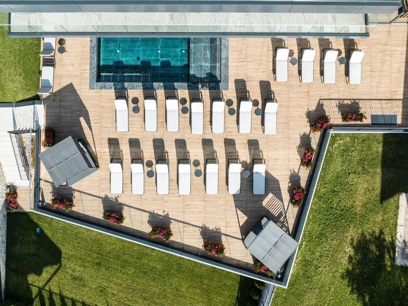 Dachterrasse mit Pool und Liegestühlen, umgeben von Grünflächen und Gebäuden.