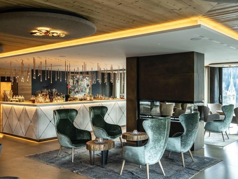 Elegante Hotelbar mit grünen Sesseln und modernem, beleuchtetem Tresen