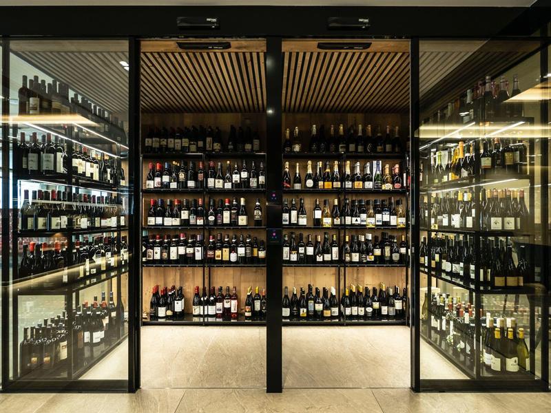 Moderner Weinkeller mit Glaswänden und einer Vielzahl von Weinflaschen in einem Hotel.