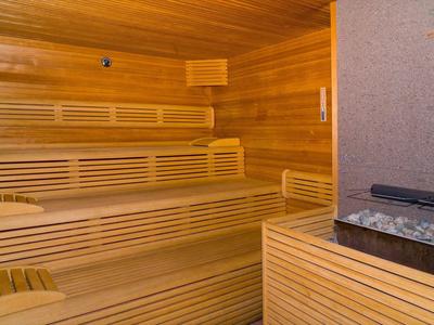 Innenraum einer Holzsauna mit Holzbänken und einem Saunaofen mit heißen Steinen.