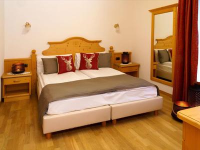 Gemütliches Schlafzimmer mit Doppelbett, Holzmöbeln und roten Akzentkissen am Kopfende.