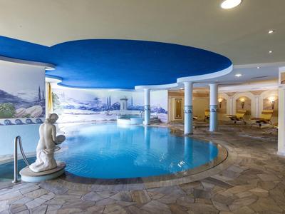 Piscina cubierta de hotel con estatua, techo azul y ventanas panorámicas