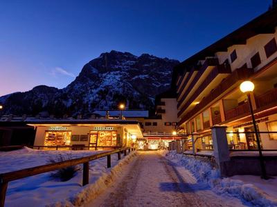 Hotel at evening with snow-covered entrance and mountain backdrop.