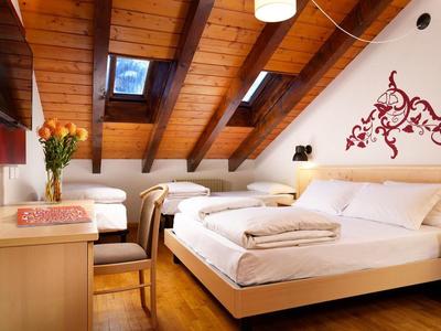 Gemütliches Schlafzimmer mit Holzdach, zwei Betten, Nachttisch und Blumen in Vase.