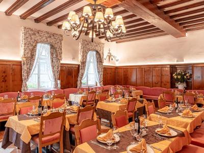 Eleganter Speisesaal mit Holzbalken, gelben Tischdecken und dekorativen Kronleuchtern.