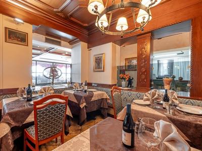 Gemütliches Restaurant mit Holzmöbeln, gedeckten Tischen und warmem Licht durch Kronleuchter.