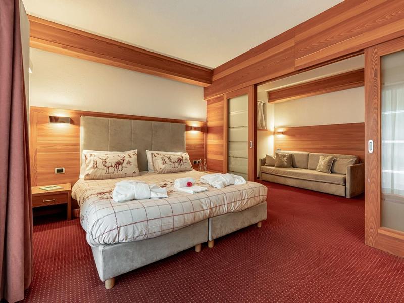 Gemütliches Hotelzimmer mit Doppelbett, Teppichboden und Sitzecke hinter Glasschiebetüren.