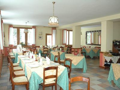 Großer Speisesaal mit blau-grünen Tischdecken, Holztischen und Stühlen, heller Raum mit Fenstern.