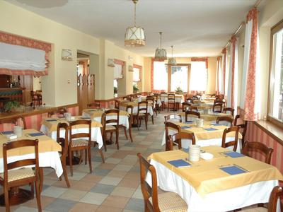 Helles, großes Restaurant mit quadratischen Tischen und Holzstühlen, Fenster an der rechten Seite